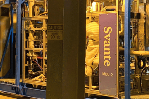 Komplexes Svante MDU-2 Prozessmodul auf blauem Rahmen in Industriehalle. Massiver Träger, Rohre, Kräne unter warmem gelben Licht.