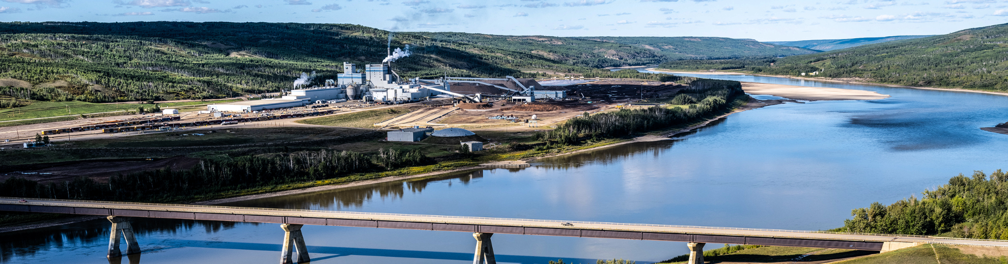 Landschaftsaufnahme vom Zellstoffwerke Mercer Peace River. Im Vordergrund eine Brücke , die über den Peace River führt.